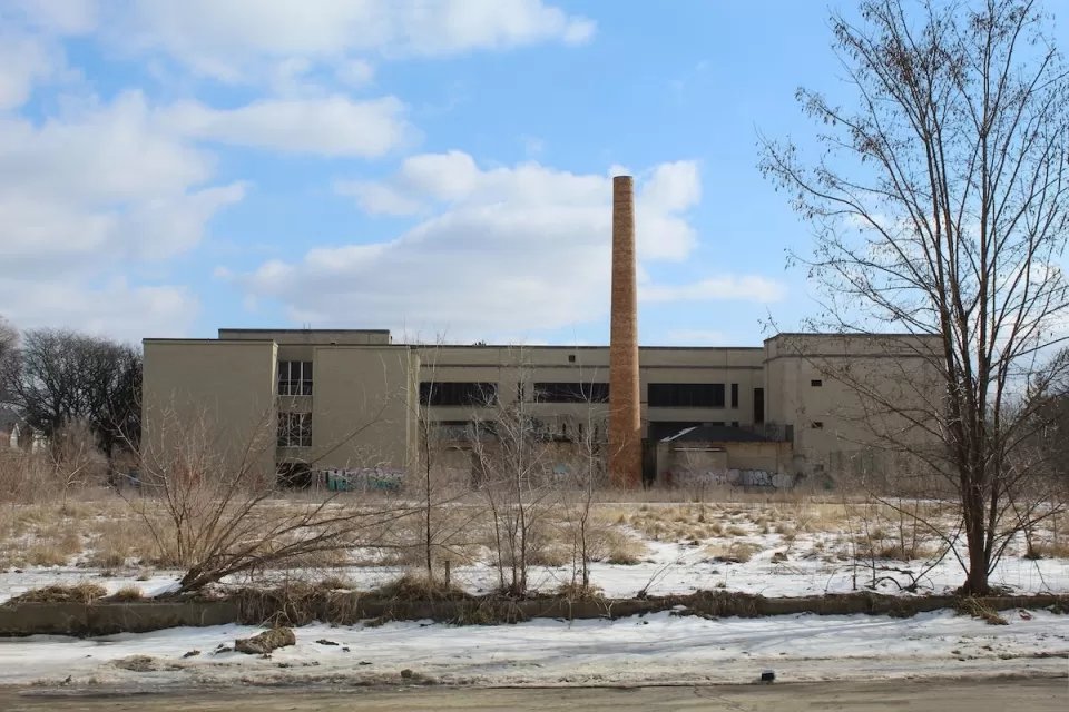 Abandoned school building with brick smokestack in winter.